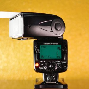 Professional studio flash lighting equipment displayed against a vibrant yellow background.