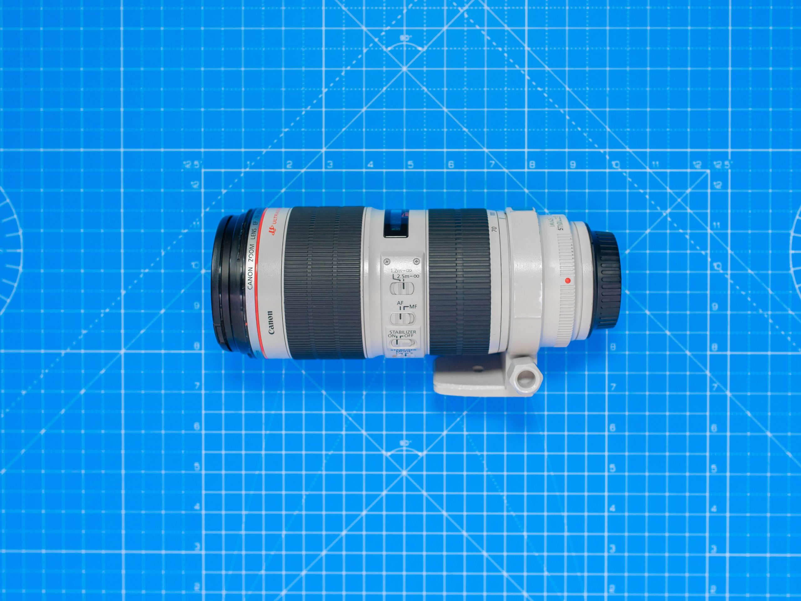 pexels photo 13826751 13826751 Top view of a professional camera zoom lens on a blue grid pattern background.