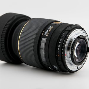 Detailed close-up of a professional camera lens against a plain white backdrop, showcasing precision design.