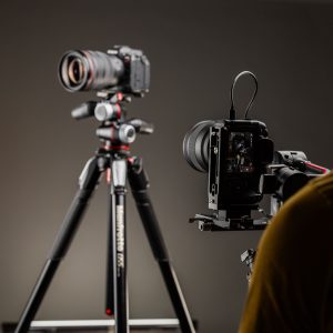 Photographer adjusting Canon camera on tripod in studio lighting setup.