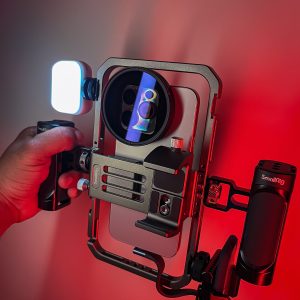 Close-up of a camera rig with LED light in a red-lit environment, capturing vibrant colors.