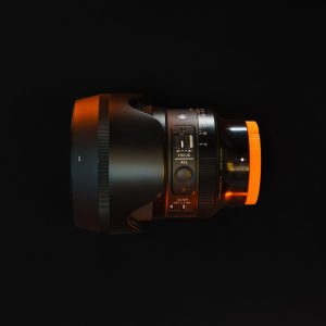 Close-up of a professional camera lens against a black backdrop. Ideal for photography equipment showcases.