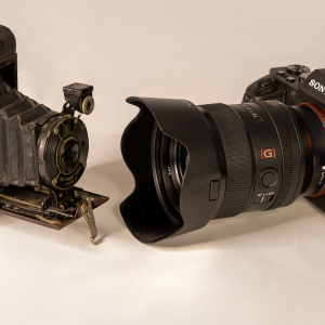 A vintage bellows camera next to a modern DSLR showcasing the evolution of photography technology.