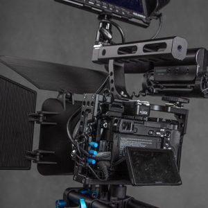 Modern black video camera cage with frame and monitor with wires placed on gray background in professional studio with equipment