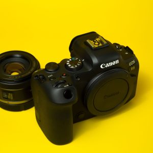 Black Canon EOS R6 camera body with a detached lens on a vibrant yellow background.