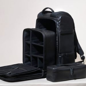 Sleek black leather camera bag showcasing compartments on a white background.